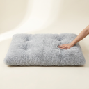 Soft plush bed next to a hand for size reference