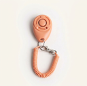 Peach dog training clicker with adjustable wrist strap, studio photo