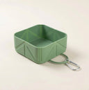 Green collapsible dog travel bowl on a cream background