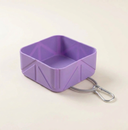 Purple collapsible dog travel bowl on a cream background