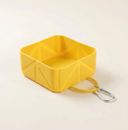 Yellow collapsible dog travel bowl on a cream background