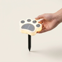Solar paw print light next to a hand for size reference