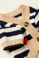 Close-up of the button closure and ribbed knit trim on the beige dog cardigan