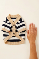 Knitted dog cardigan next to a hand for size reference